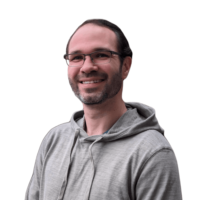 Andy Ernst smiling. A 30-something white man with glasses, hair pulled back into a ponytail